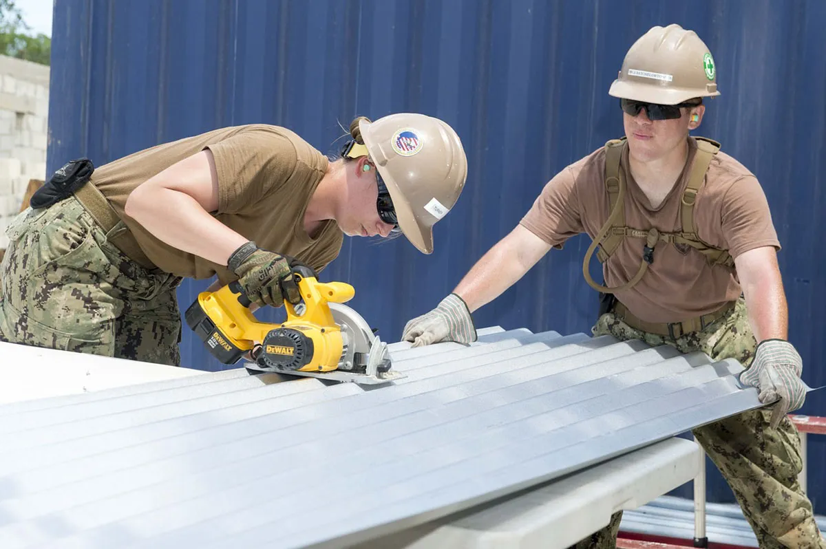 Two contractors in hard hats installing metal roofing panels