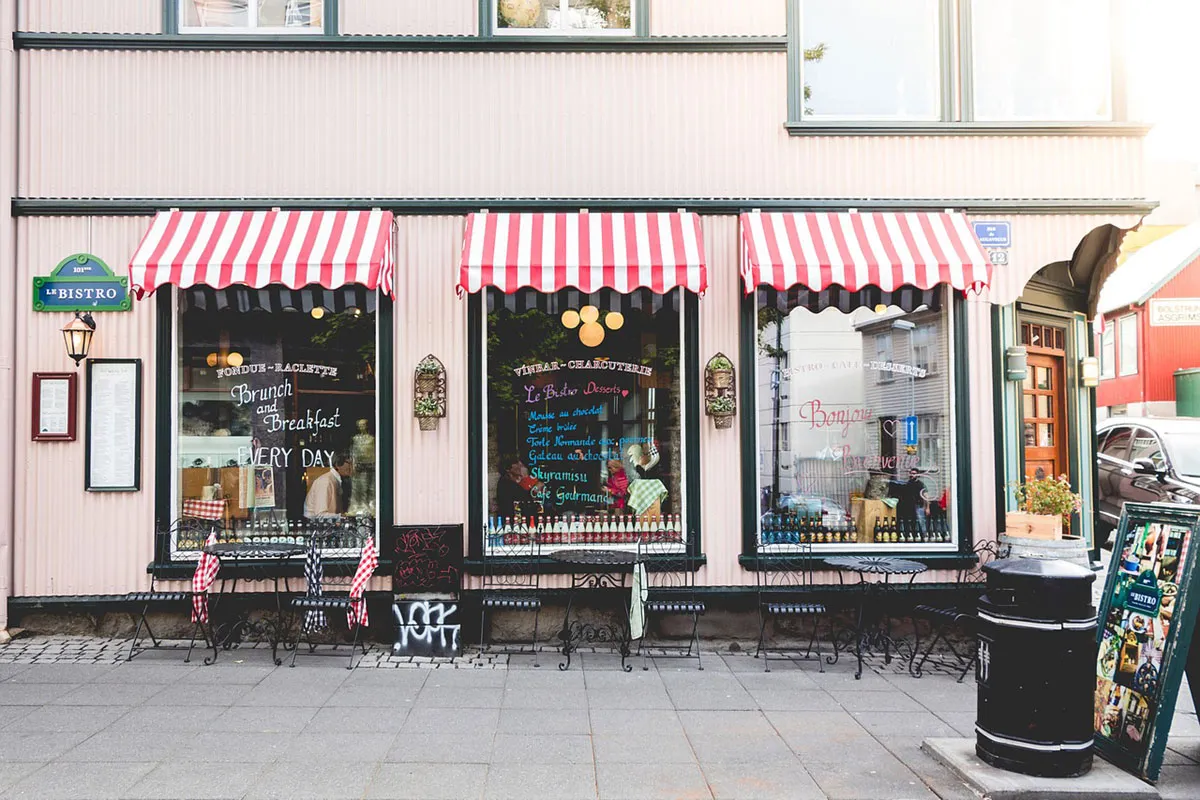 A small shopfront with striped awnings and outdoor seating