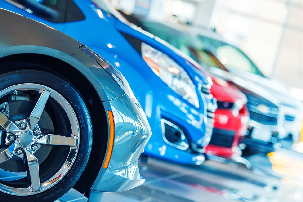 A row of parked cars with focus on a car wheel and rim