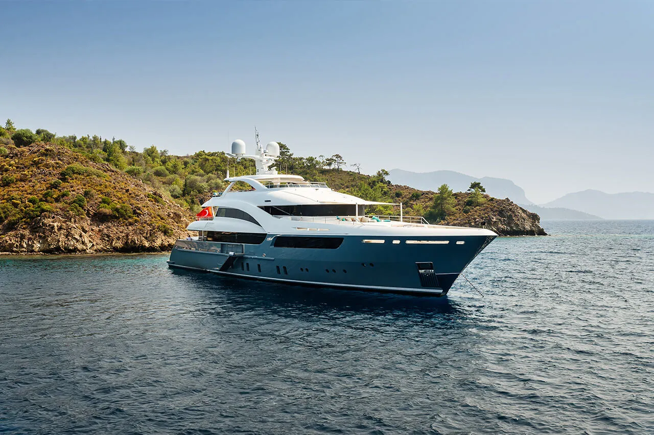 A motor yacht anchored near a rocky coastline