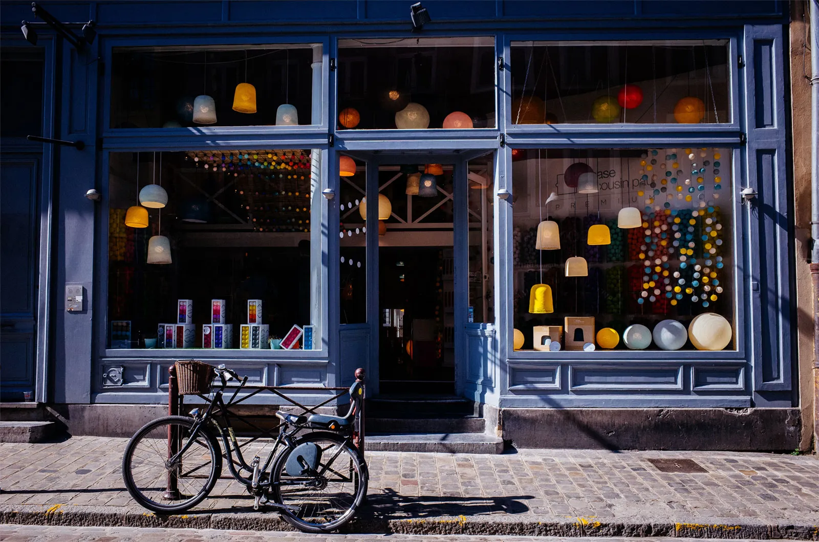 A blue-painted shopfront with lantern displays in the windows and a bicycle parked outside